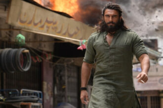 रणवीर सिंह धुरंधर फिल्म के पोस्टर के साथ एक्शन अंदाज में”