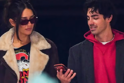 जो जोनस और उनकी प्रेमिका टाटियाना गैब्रिएला समुद्र तट पर हाथ में हाथ डाले खड़े, मुस्कुराते हुए