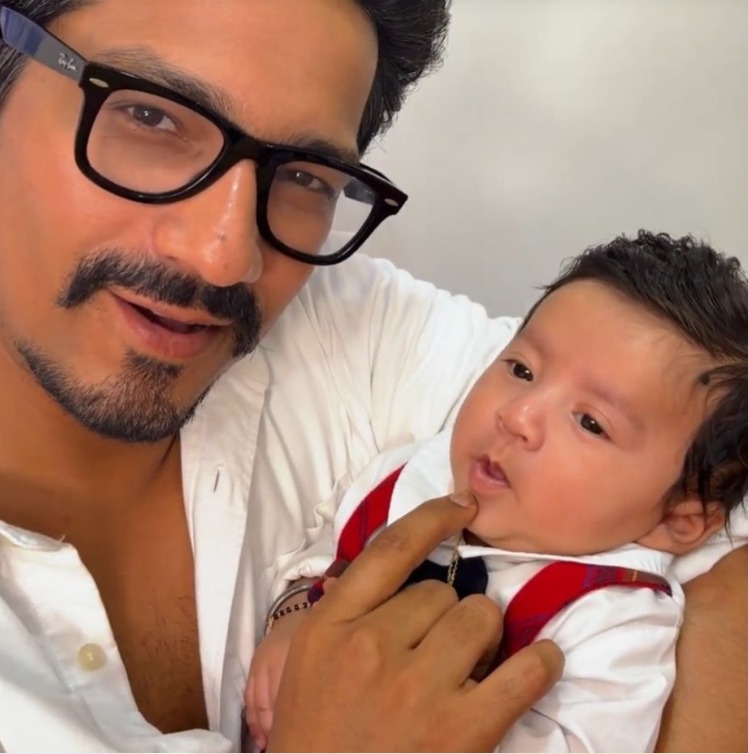 भारती सिंह और हर्ष लिम्बाचिया अपने दूसरे बेटे यशवीर उर्फ काजू को गोद में लिए हुए, फेस रिवील के दौरान मुस्कुराते नजर आ रहे हैं।