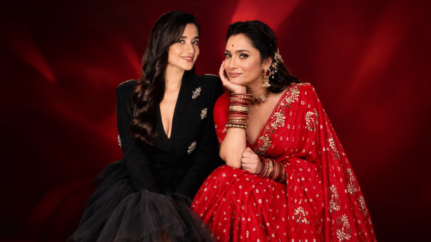 Two women posing together in stylish black and red outfits against a red backdrop.