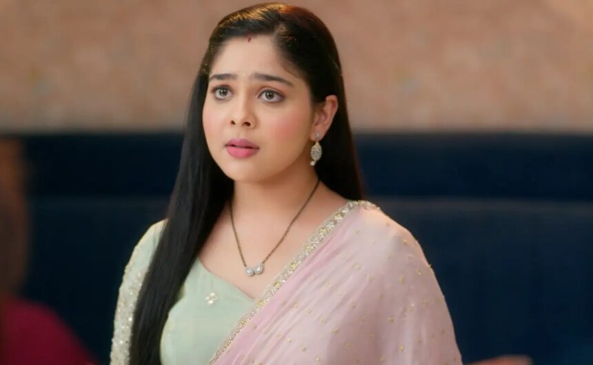 A woman wearing a pastel green blouse and pink saree, looking emotional and surprised indoors.