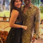 A smiling couple posing together at an event in traditional and festive outfits.
