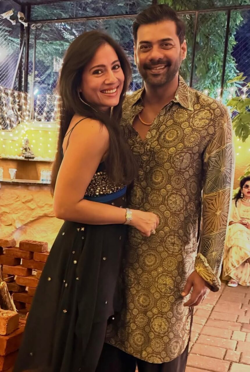 A smiling couple posing together at an event in traditional and festive outfits.