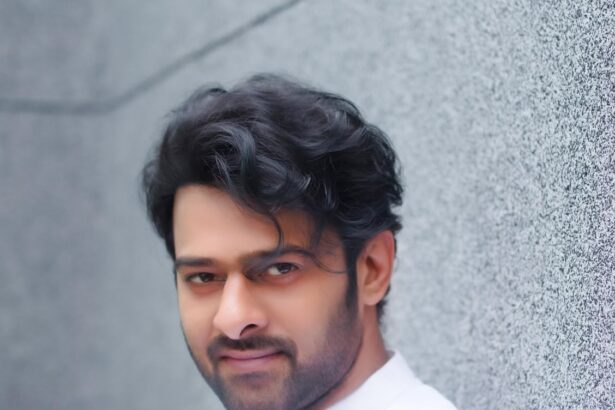 prabhas in a white outfit posting against a grey textured wall