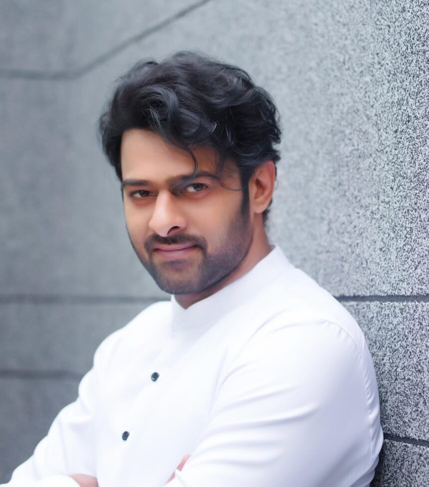 prabhas in a white outfit posting against a grey textured wall